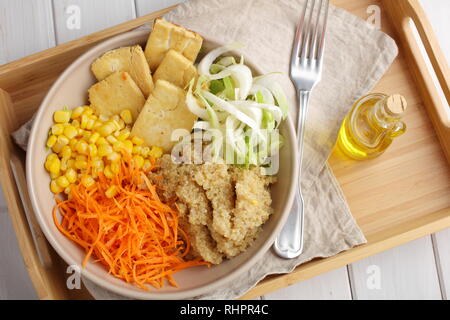 Ciotola di Buddha con la quinoa, tofu fritto, cicoria, carota, mais e olio di oliva Foto Stock