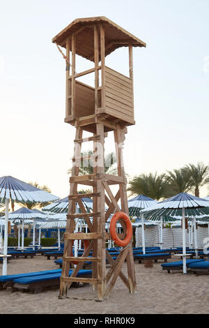 Bagnino in legno torre sulla spiaggia di sabbia. Blue chaises longues e palme sullo sfondo Foto Stock