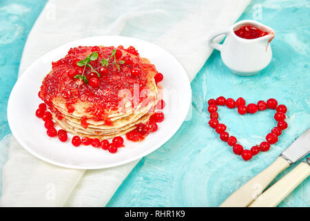 Cuore dal Berry. American pancake con la marmellata - berry, pallon di maggio, mirtillo rosso su sfondo blu. Pancake fatti in casa con salsa di frutti di bosco e le foglie di menta. Brea sani Foto Stock