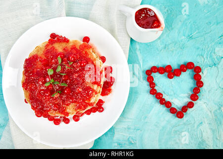 Cuore dal Berry. American pancake con la marmellata - berry, pallon di maggio, mirtillo rosso su sfondo blu. Pancake fatti in casa con salsa di frutti di bosco e le foglie di menta. Brea sani Foto Stock