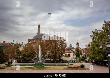 SOFIA, BULGARIA - 14 ottobre 2018: Molte persone godono di aspersione di acqua di fontane in Piazza Banski nella capitale bulgara. Moody cielo nuvoloso giorno d'autunno. Vista dalla scalinata del Museo di Storia Foto Stock