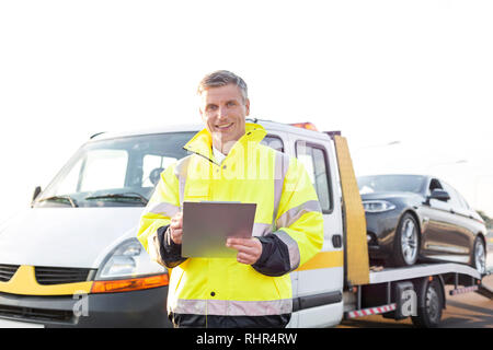 Ritratto di sorridere carroattrezzi driver con appunti contro sky Foto Stock