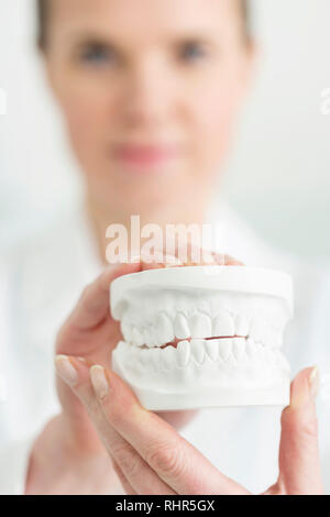 Close-up di dentista femmina bianco di contenimento dentiere presso la clinica Foto Stock