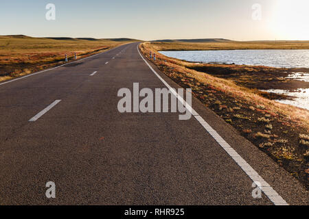 Strada asfaltata nella steppa Mongola lungo un piccolo lago, Mongolia Foto Stock