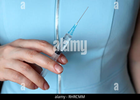 Medico con una siringa, donna in blue coat preparazione per iniezione. Concetto di vaccinazione, il trattamento in clinica di chirurgia plastica Foto Stock