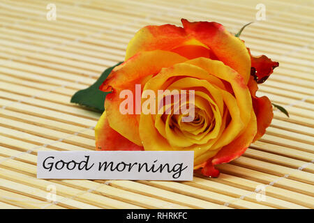 Buona mattina scheda con uno rosso e rosa gialla cosparso con glitter sul tappetino di bambù Foto Stock