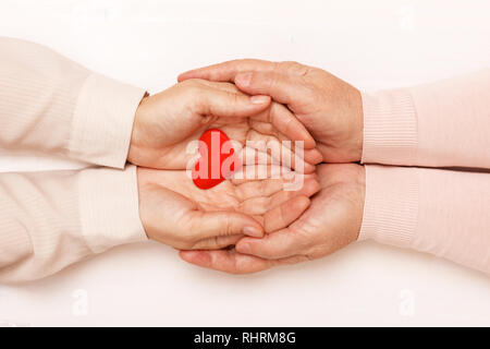 Close-up della mano di un adulto figlia e una vecchia madre tenendo un cuore insieme. Vista dall'alto. La famiglia e il concetto di cura Foto Stock