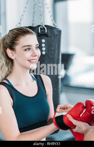 Sorridente giovani sportive indossando guanti di inscatolamento e guardando lontano in palestra Foto Stock