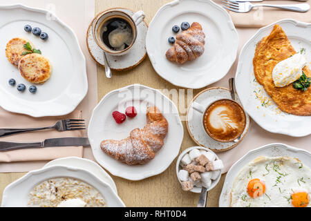 La prima colazione. Cornetti, caffè e diversi piatti sul tavolo del ristorante. Frittata - omelette italiano. Frittata con pomodori, avocado Foto Stock