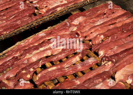 Cambogia, Phnom Penh, Street 19 , cibo, speziato con la carne di maiale appassimento sui graticci nella luce del sole Foto Stock
