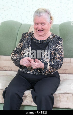 Nonna conta sulle sue dita mentre è seduto su un divano in camera Foto Stock
