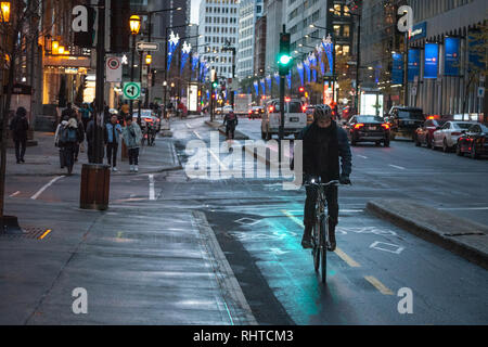 MONTREAL, Canada - 7 Novembre 2018: ciclista, consegna courrier guy, in piedi con la sua bicicletta su una pista ciclabile nel centro storico quartiere degli affari Foto Stock