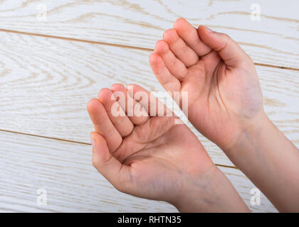 Le mani facendo pregare gesto su uno sfondo di legno Foto Stock
