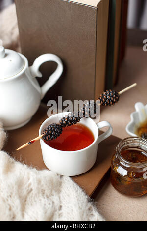 Tazza di tè con dolcezza siberiano - coni di zucchero, teiera e vecchi libri sullo sfondo di legno, concetto di accogliente teatime, autunno inverno weekend, tempo libero t Foto Stock