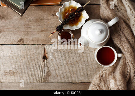 Tazza di tè con dolcezza siberiano - coni di zucchero, teiera e vecchi libri sullo sfondo di legno, concetto di accogliente teatime, autunno inverno weekend, tempo libero t Foto Stock