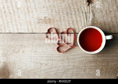 Tazza di tè a forma di cuore su vintage tavolo in legno, la minima nozione di valentine madre giorno mattina la prima colazione Foto Stock