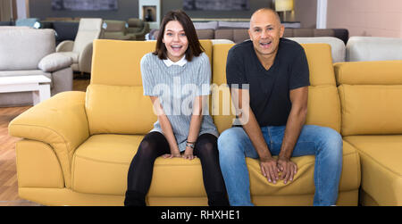 Ritratto di amare giovane seduto sul divano giallo nel salone di mobili in camera shopping Foto Stock