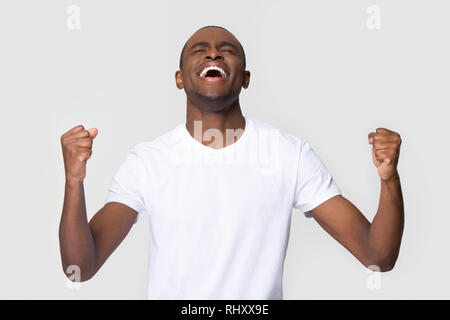 Overjoyed felice giovane americano africano uomo trionfale per celebrare la vittoria Foto Stock