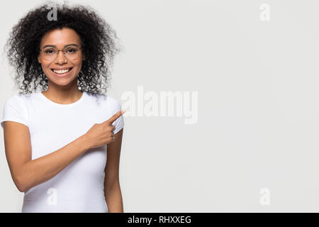 Sorridente donna africana in bicchieri pubblicità puntare il dito a copyspace Foto Stock