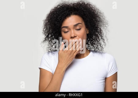 Stanco americano africano donna sbadigli isolato su bianco di sfondo per studio Foto Stock