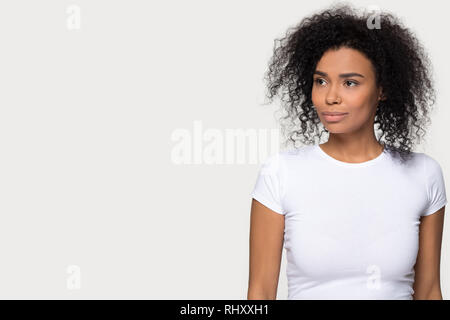 Fiducioso premurosa donna nera che guarda lontano sognando isolato su sfondo Foto Stock