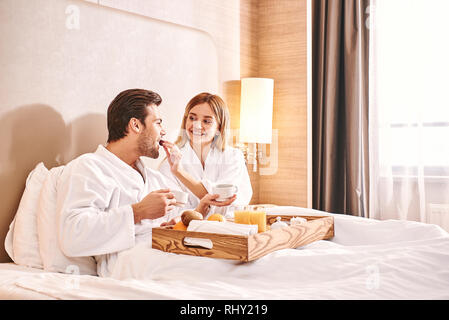 Alimentazione di ogni altro. Coppia sono di mangiare in hotel camera letto insieme. Storia d'amore. Foto Stock