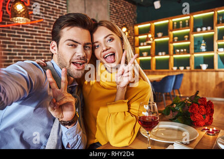 Funny giovane fare foto. Coppia giovane sorridente e rendendo selfie foto sul telefono mentre a cena, close-up Foto Stock