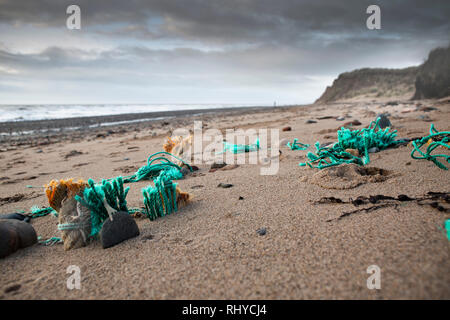 Scartare le reti da pesca incorporato nella sabbia sulla spiaggia del Regno Unito una grave forma di inquinamento in plastica. Foto Stock