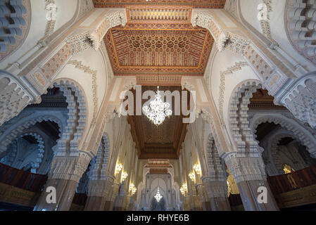 All'interno della moschea di Hassan II con corridoio interno con colonne. Archi arabi, ornamenti, lampadario e illuminazione. Casablanca, Marocco la più grande moschea Foto Stock