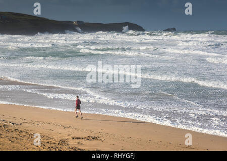 Un uomo che corre lungo il litorale su Fistral Beach in Newquay Cornwall. Foto Stock