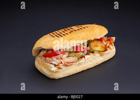 Ciabatta pane farcito con formaggio,carni e verdure su sfondo scuro,fuoco selettivo e uno spazio vuoto Foto Stock