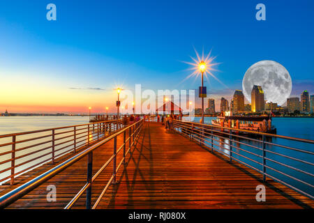 Scenic twiligtht vista di Coronado molo in legno con agganciato ferry boat su Coronado Island, California, Stati Uniti d'America. San Diego skyline e il centro urbano Foto Stock