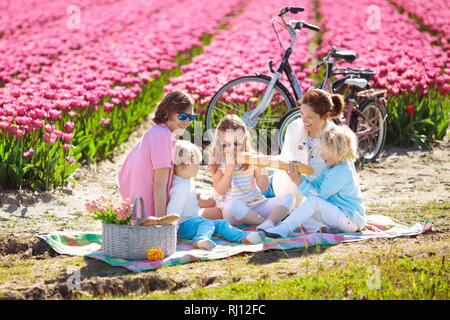 Picnic in famiglia al tulip campi di fiori in Olanda. Giovane madre e bambini a mangiare il pranzo in fioritura di tulipani di Campo dei Fiori. La mamma e i bambini viaggiare in bicicletta. Foto Stock