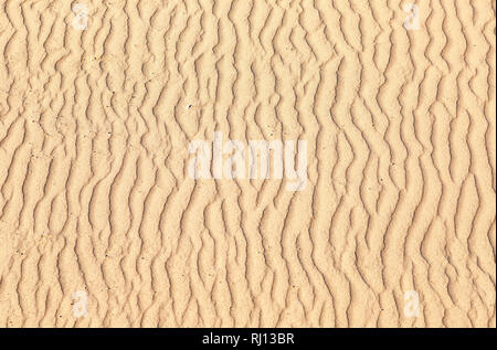 Texture naturali della superficie della spiaggia di sabbia. Onde sulla sabbia come sfondo Foto Stock