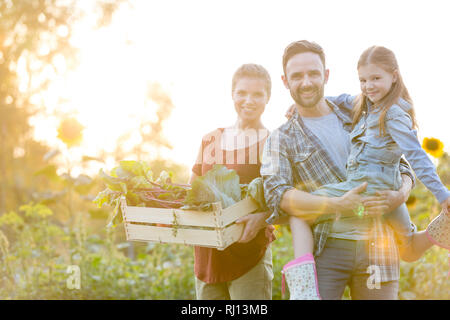 Ritratto di famiglia sorridente con verdure in cassa presso l'azienda Foto Stock