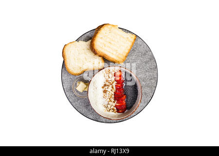 Una sana prima colazione. Cereali di riso o porridge con fragole fresche, mandorla e scaglie di noce di cocco, servita con pane e burro. Isolato sul bianco Foto Stock