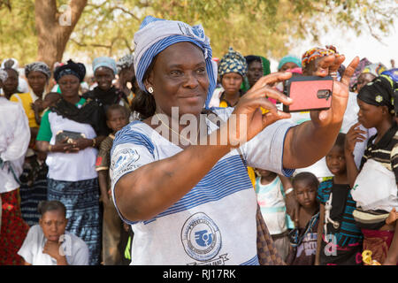 Città Kisi, Burkina Faso; una donna scatta una foto sul suo telefono cellulare sulla giornata internazionale della donna una festività nazionale. Foto Stock