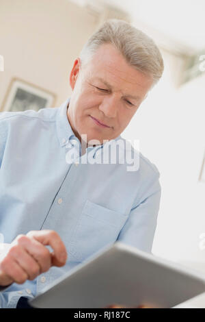 Uomo maturo con tavoletta digitale in casa Foto Stock