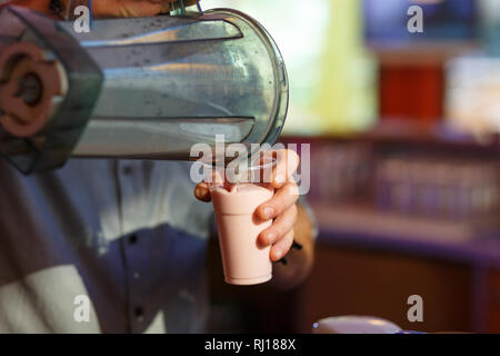 La mano del barista, versa il frullato in un bicchiere. Foto Stock