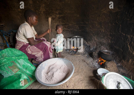 Il villaggio di Samba, Provincia Yako, Burkina Faso : Collette Guiguemde, 26 con il bambino e i suoi quattro anni, figlia, libbre cile per andare con un pasto di okra ha appena raccolto e di sorgo di porridge. Foto Stock