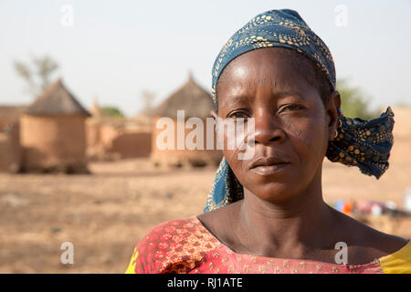 Villaggio Kourono, provincia Yako, Burkina Faso; un ritratto di una donna con marcatura tribali sul suo volto, nella parte anteriore del villaggio di negozi di granella. Foto Stock