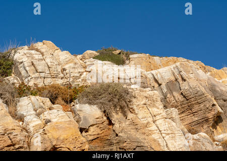 Consistenza naturale di rocce contro il cielo blu. Incrinato e stagionato in pietra naturale sullo sfondo Foto Stock