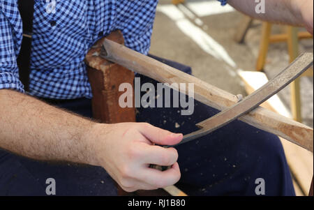 Carpenter utilizza un vecchio ruspa per pianificare il legno di un bastone Foto Stock