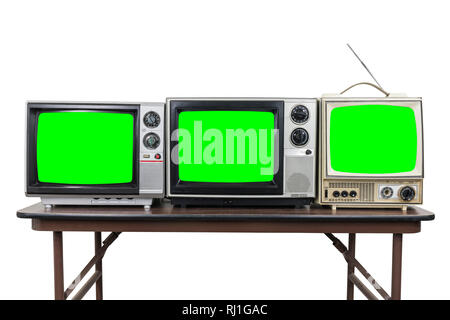 Tre televisori vintage sulla tavola di legno isolato su bianco con chroma key green schermate. Foto Stock