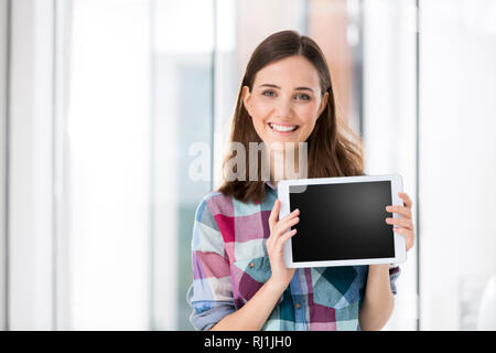 Ritratto di felice imprenditrice che mostra una schermata vuota di tavoletta digitale Foto Stock