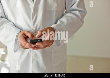 Controllo medico il suo telefono cellulare. Foto Stock