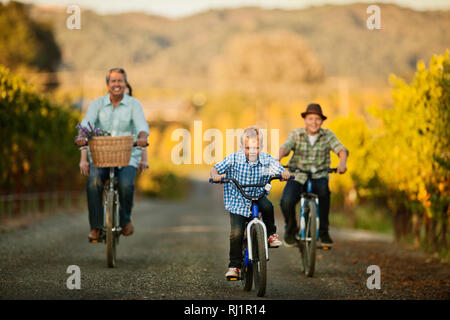 Little Boy in sella alla sua bicicletta con suo fratello e padre. Foto Stock