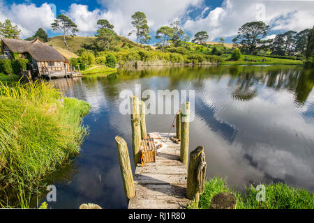 MataMata, Nuova Zelanda - Marzo 2017 Hobbit house e il vecchio mulino accanto a un vecchio ponte lapideo Hobbiton Foto Stock