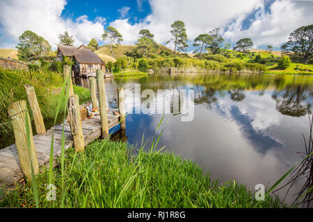 MataMata, Nuova Zelanda - Marzo 2017 Hobbit house e il vecchio mulino accanto a un vecchio ponte lapideo Hobbiton Foto Stock