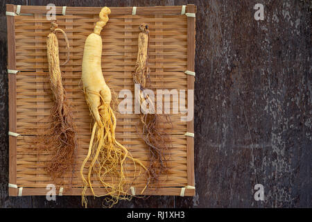 Gingseng sull intreccio di bambù con copia spazio su uno sfondo di legno. Foto Stock